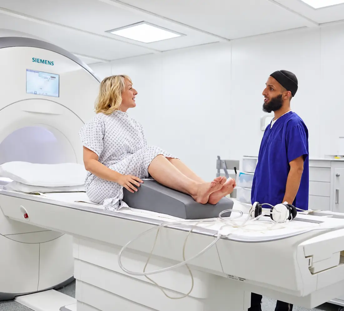 A radiographer talking with a patient on an MRI table